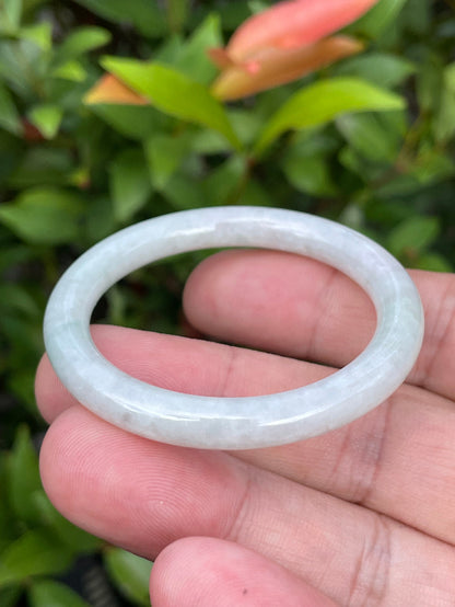 Handcrafted genuine Grade A Burmese jadeite infant bangle showcasing a translucent bright green and white appearance