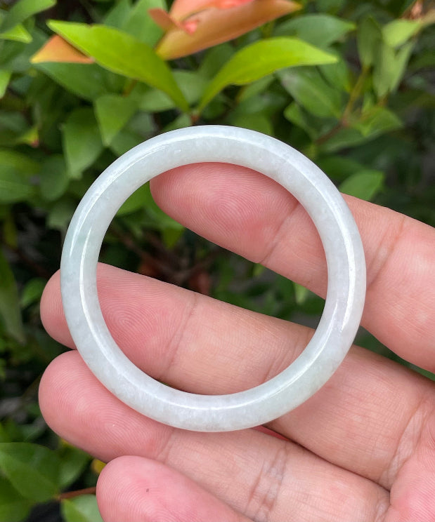 Handcrafted genuine Grade A Burmese jadeite infant bangle showcasing a translucent bright green and white appearance