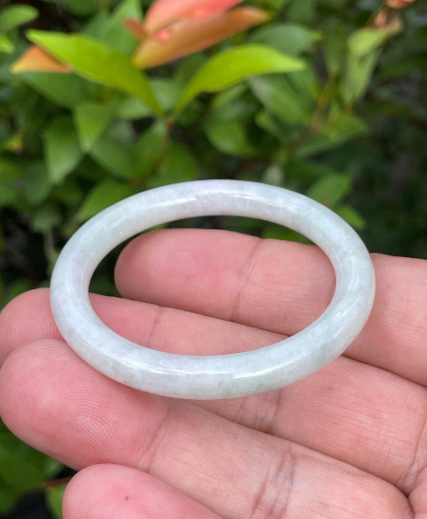 Handcrafted genuine Grade A Burmese jadeite infant bangle showcasing a translucent bright green and white appearance