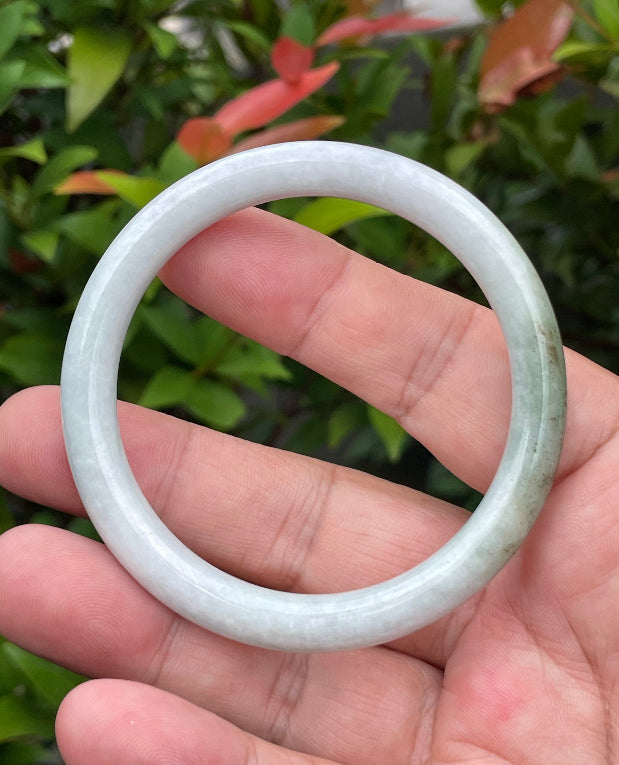 Close-up of a 55.9mm natural Grade A Burmese jadeite bangle featuring icy milky white and moss green hues, item JB871