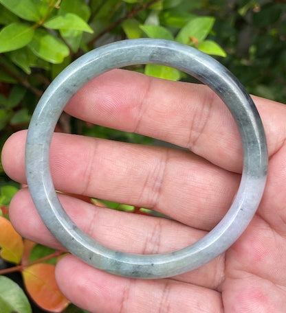 Close-up of a 57.5mm natural Grade A Burmese jadeite bangle featuring tricolor moss green, black, and milky white hues, item JB958