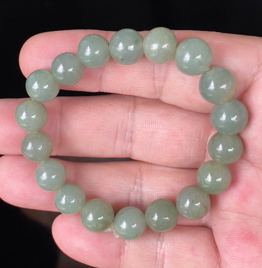 Close-up of a 10.5mm natural Grade A Burmese jadeite beaded bracelet featuring hand-shaped icy apple green beads, item JBB128