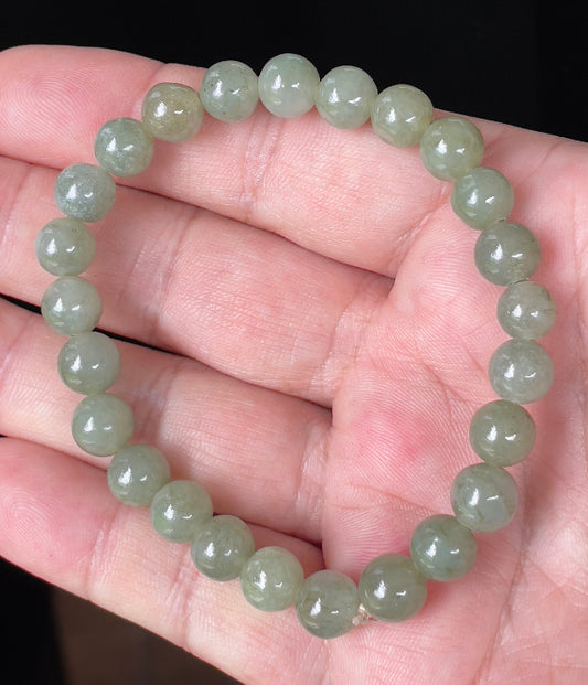 Close-up of an 8.2mm natural Grade A Burmese jadeite beaded bracelet featuring icy apple green hues, item JBB124