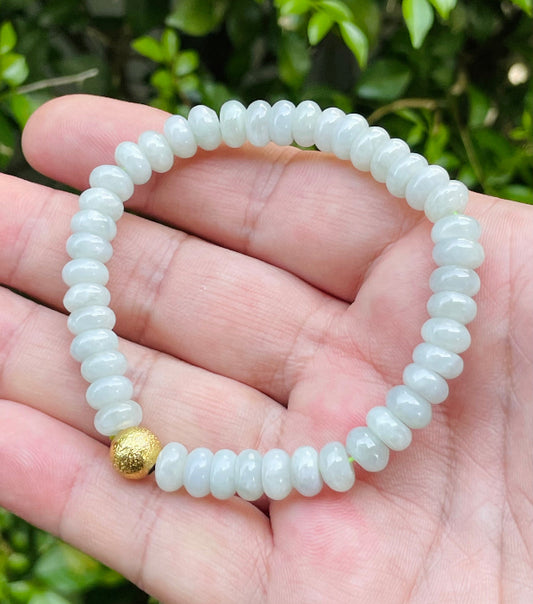 Close-up of a 7.5mm natural Grade A Burmese jadeite beaded bracelet featuring icy apple green donut-style beads and a gold accent bead, item JBB169
