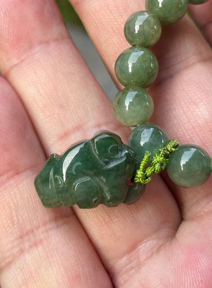 Handcrafted genuine Grade A Burmese jadeite stretch bracelet showcasing beautiful icy deep mossy green beads with a hand-carved Pixiu pendant