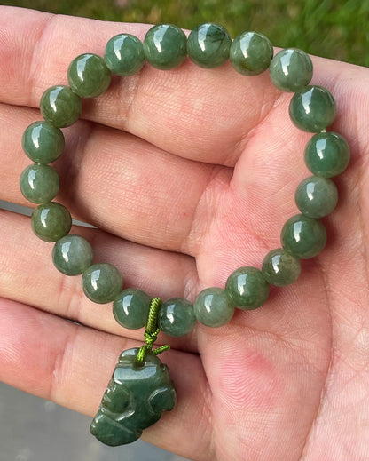 Handcrafted genuine Grade A Burmese jadeite stretch bracelet showcasing beautiful icy deep mossy green beads with a hand-carved Pixiu pendant