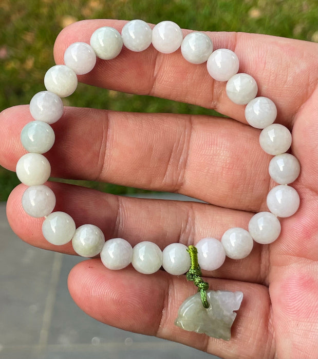 Handcrafted genuine Grade A Burmese jadeite stretch bracelet showcasing beautiful icy milky white and apple green beads with a hand-carved tiger pendant