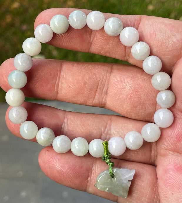 Handcrafted genuine Grade A Burmese jadeite stretch bracelet showcasing beautiful icy milky white and apple green beads with a hand-carved tiger pendant