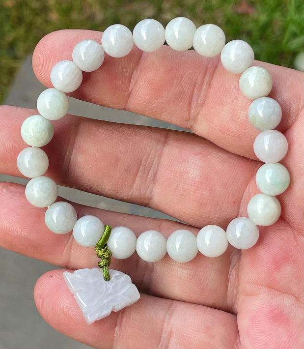 Close-up of an 8mm natural Grade A Burmese jadeite beaded bracelet featuring milky white and faint apple green beads with a tiger pendant, item JBB180