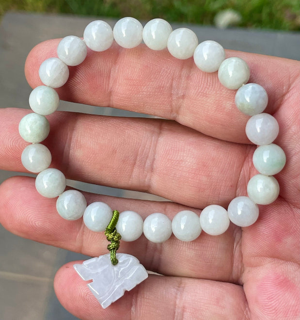 Handcrafted genuine Grade A Burmese jadeite stretch bracelet showcasing beautiful milky white and icy apple green beads with a hand-carved tiger pendant