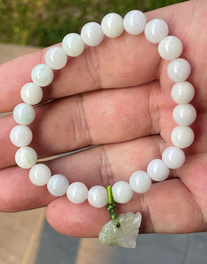 Handcrafted genuine Grade A Burmese jadeite stretch bracelet showcasing beautiful milky white and light lavender beads with a hand-carved tiger pendant