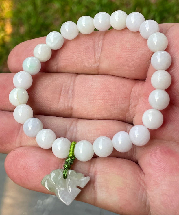 Handcrafted genuine Grade A Burmese jadeite stretch bracelet showcasing beautiful milky white and light lavender beads with a hand-carved tiger pendant