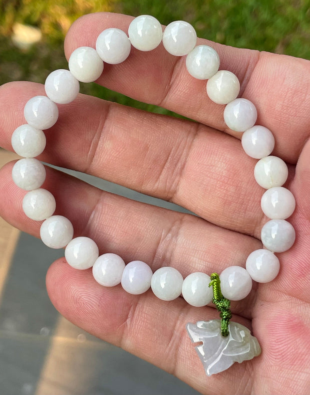 Handcrafted genuine Grade A Burmese jadeite stretch bracelet showcasing beautiful milky white and light lavender beads with a hand-carved tiger pendant