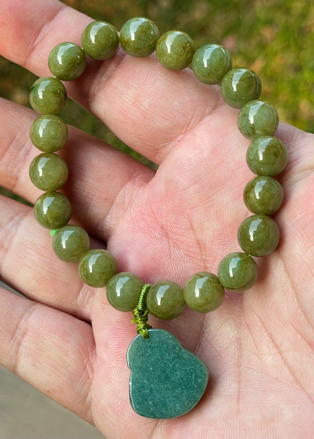 Handcrafted genuine Grade A Burmese jadeite stretch bracelet showcasing beautiful olive green beads with a hand-carved Laughing Buddha pendant