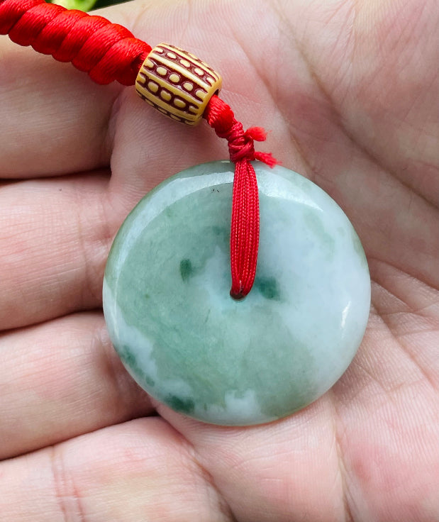 Close-up of a natural Grade A Burmese jadeite pendant featuring a tranquil blend of forest green and milky white tones in a round disc shape, item JP061
