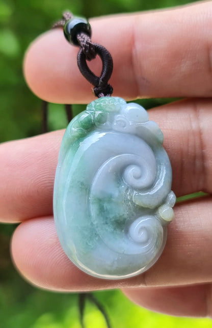 Close-up of a natural Grade A Burmese jadeite pendant featuring milky white and imperial green tones hand-carved in a ruyi scroll motif, item JP022