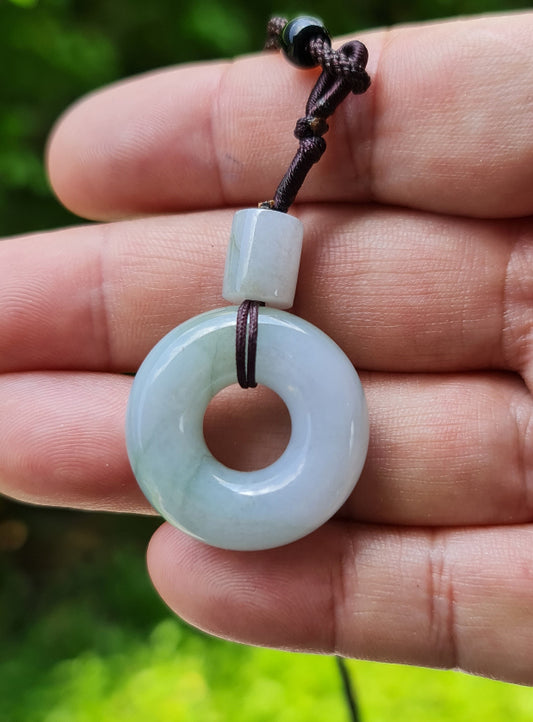 Close-up of a natural Grade A Burmese jadeite pendant featuring icy lavender and imperial green hues in a donut disc shape, item JP025