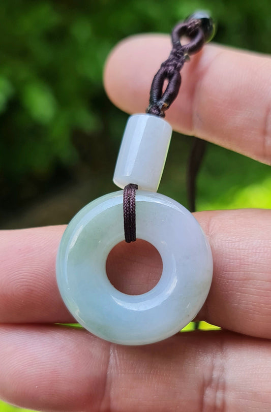 Close-up of a natural Grade A Burmese jadeite pendant featuring icy lavender and imperial green hues in a donut swirl shape, item JP024