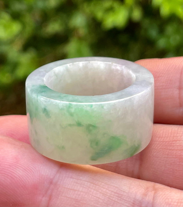 Close-up of a wide tube thumb band natural Grade A Burmese jadeite ring featuring icy green and milky white hues, item JRN023