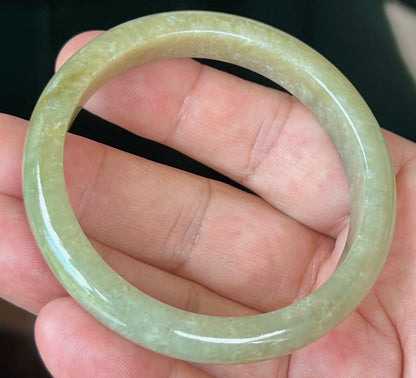 Close-up of light honey hues on icy apple green jadeite bangle