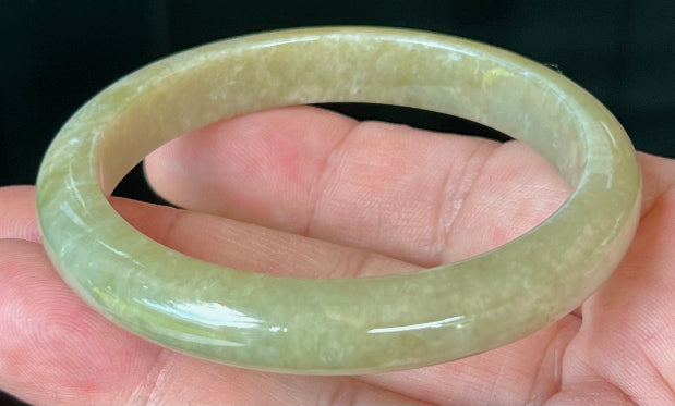Close-up of light honey hues on icy apple green jadeite bangle