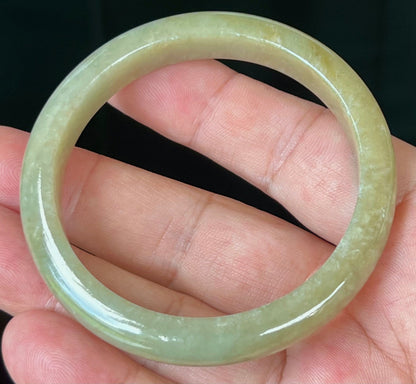 Close-up of light honey hues on icy apple green jadeite bangle