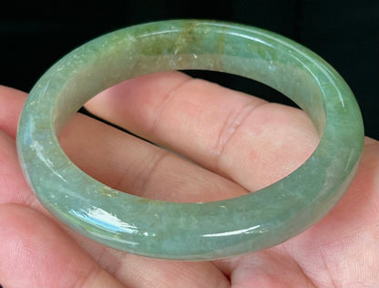 Close-up of forest green and honey hues on icy apple green jadeite bangle