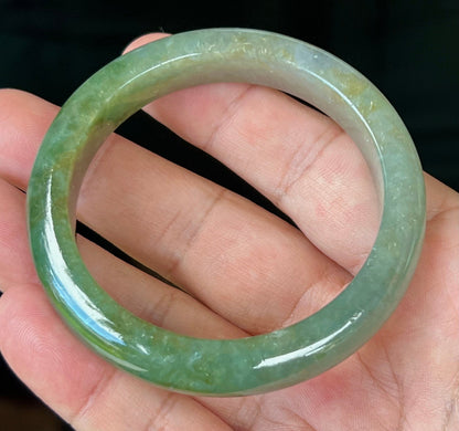 Close-up of forest green and honey hues on icy apple green jadeite bangle