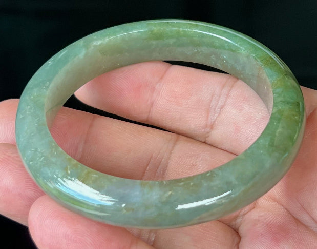 Close-up of forest green and honey hues on icy apple green jadeite bangle