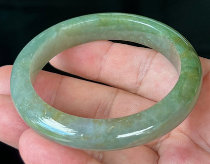 Close-up of forest green and honey hues on icy apple green jadeite bangle