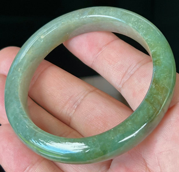 Close-up of forest green and honey hues on icy apple green jadeite bangle