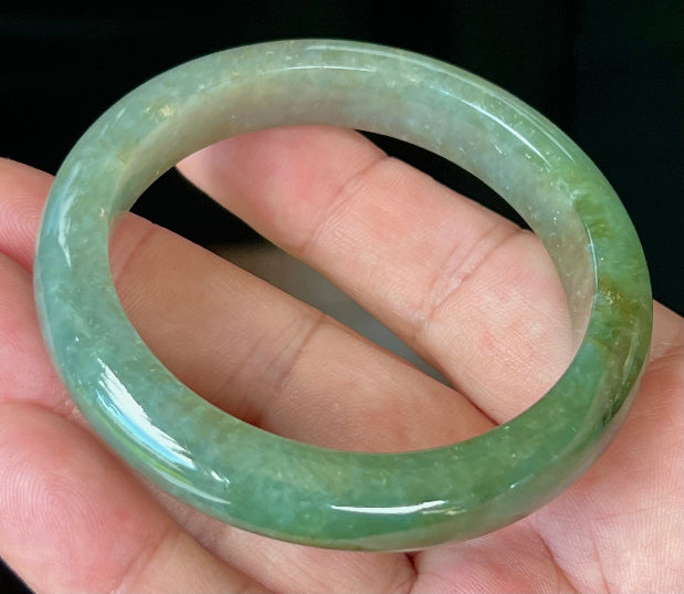 Close-up of forest green and honey hues on icy apple green jadeite bangle