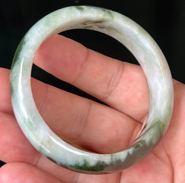 Close-up of deep forest green and milky white marbling on apple green jadeite bangle