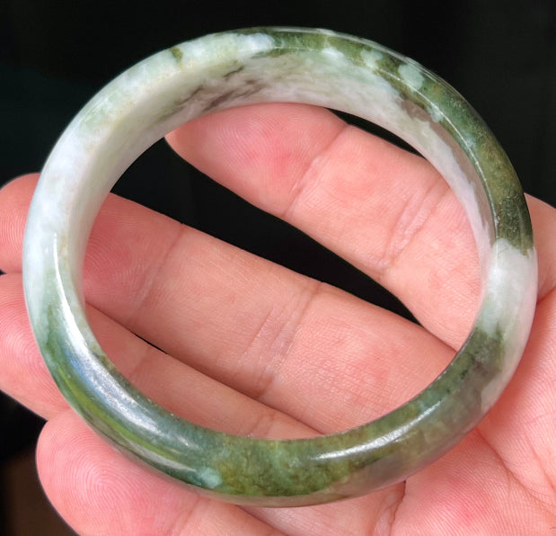 Close-up of deep forest green and milky white marbling on apple green jadeite bangle