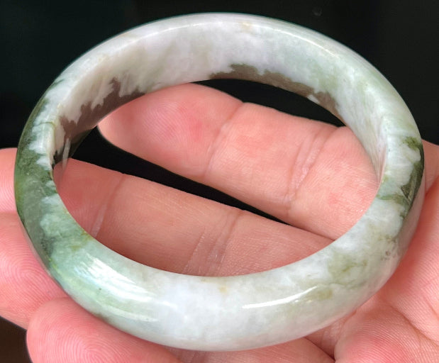Close-up of deep forest green and milky white marbling on apple green jadeite bangle