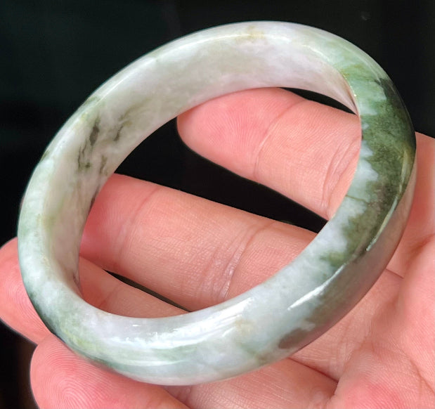 Close-up of deep forest green and milky white marbling on apple green jadeite bangle