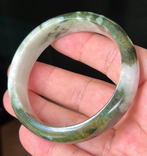 Close-up of deep forest green and milky white marbling on apple green jadeite bangle