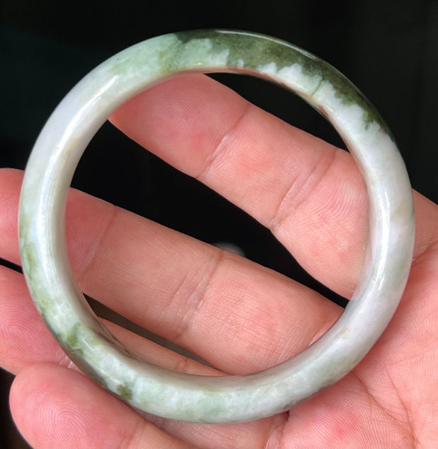 Close-up of deep forest green and milky white marbling on apple green jadeite bangle