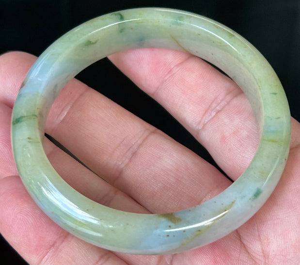 Close-up of imperial green and honey hues on icy apple jadeite bangle