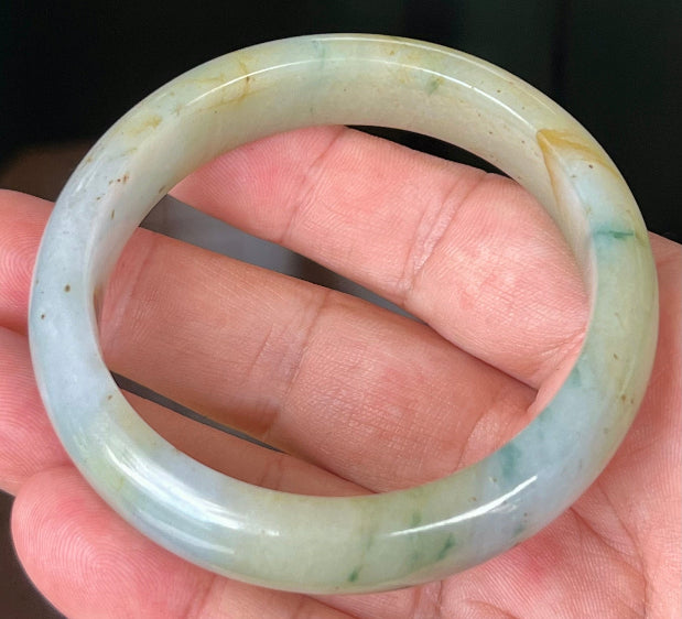 Close-up of imperial green and honey hues on icy apple jadeite bangle