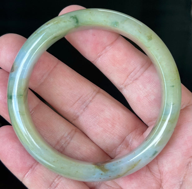 Close-up of imperial green and honey hues on icy apple jadeite bangle