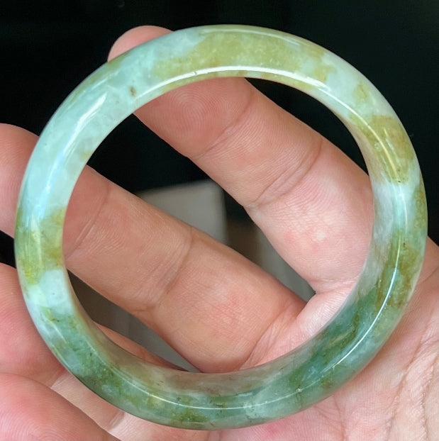 Close-up of moss green and milky white hues on icy apple green jadeite bangle