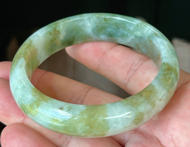 Close-up of moss green and milky white hues on icy apple green jadeite bangle