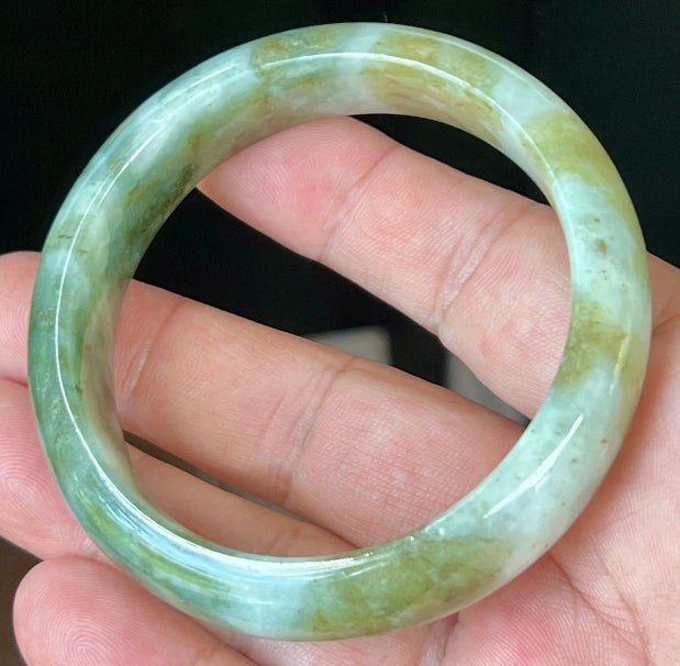 Close-up of moss green and milky white hues on icy apple green jadeite bangle