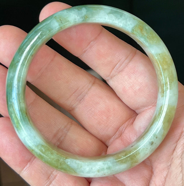 Close-up of moss green and milky white hues on icy apple green jadeite bangle
