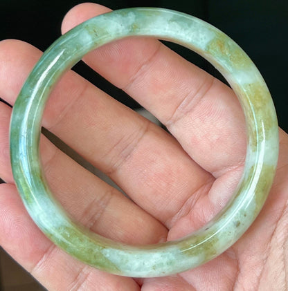 Close-up of moss green and milky white hues on icy apple green jadeite bangle