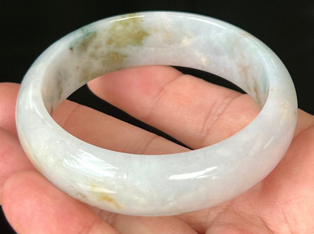 Close-up of red and moss green hues on icy apple green jadeite bangle