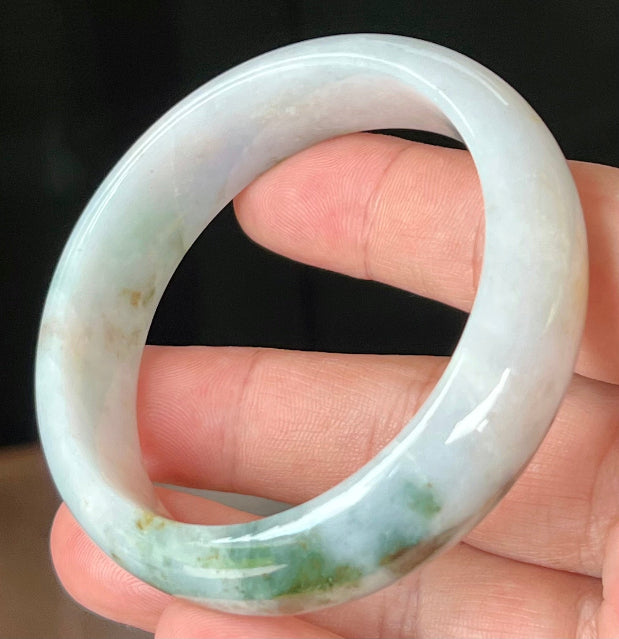 Close-up of red and moss green hues on icy apple green jadeite bangle