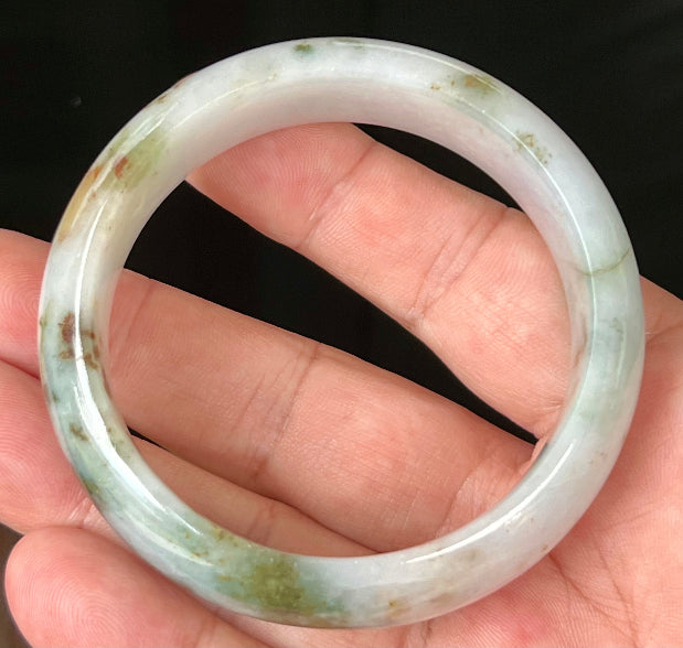 Close-up of red and moss green hues on icy apple green jadeite bangle