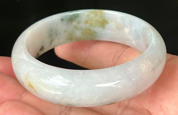 Close-up of red and moss green hues on icy apple green jadeite bangle